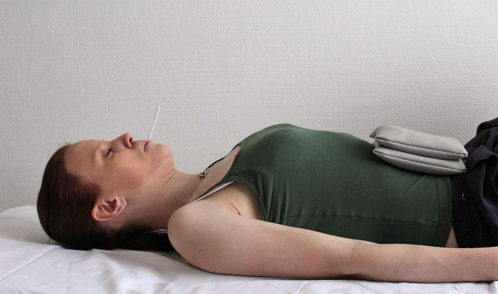 Liegende Frau demonstriert die PEP Atmung in Rückenlage