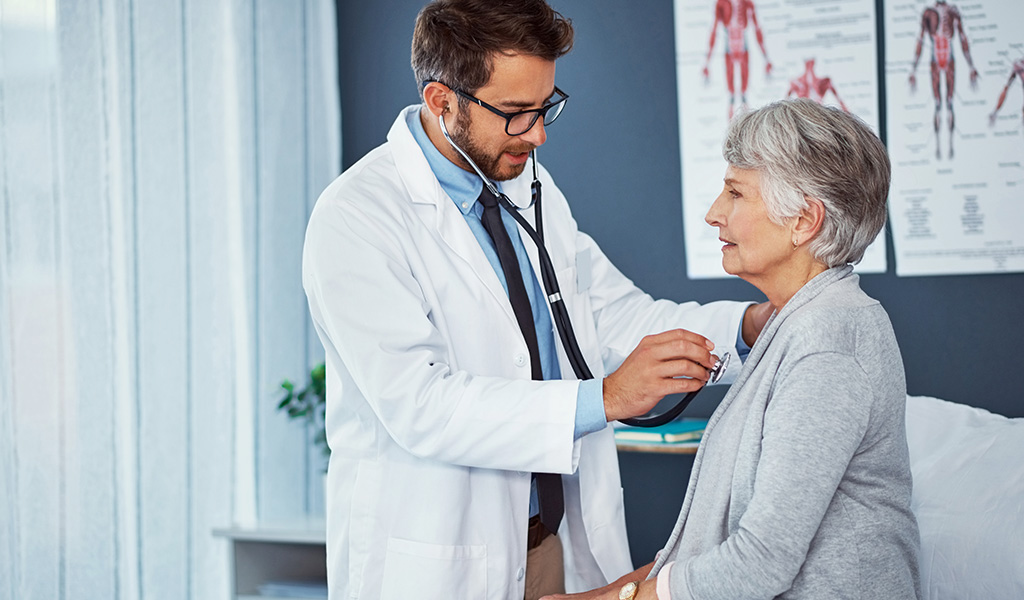 Arzt beim Abhören der Lunge einer Seniorin