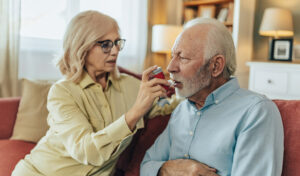 Frau hilft Ehemann, Inhalator zu Hause zu benutzen