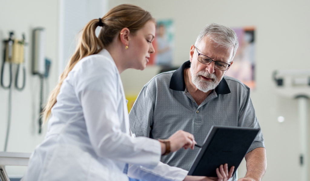 Eine ältere Patientin trainiert während einer Reha bei COPD mit kleinen Hanteln. Eine Physiotherapeutin unterstützt sie dabei.