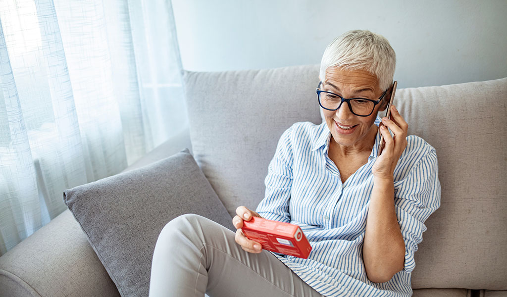 Frau am Telefon mit Medikament