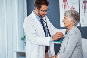 Arzt beim Abhören der Lunge einer Seniorin