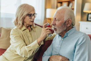 Frau hilft Ehemann, Inhalator zu Hause zu benutzen