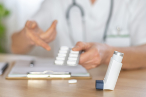 Arzt zeigt eine Blisterpackung mit Kortikosteroid-Pillen und einen Inhalator